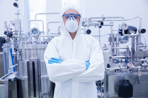 Scientist in protective suit standing with arms crossed in the factory